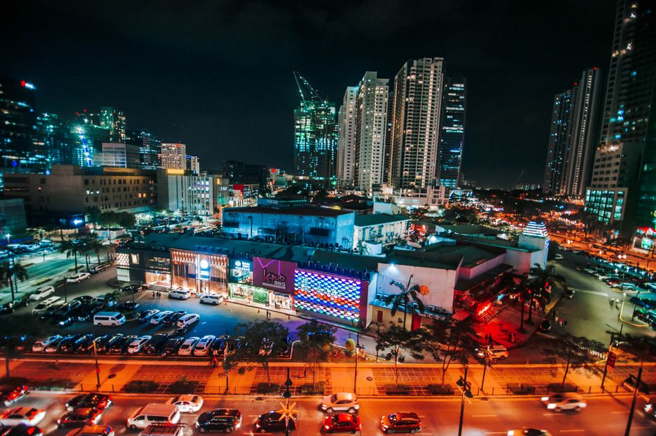 Dynamic cityscape of Taguig at night with illuminated skyscrapers and bustling traffic.